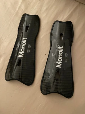 Monolit benskydd i kolfiber - Säljer ett par svarta benskydd från Monolit i kolfiber. De är superlätta, väger ca 40 gram och har en slimmad, ergonomisk form för bästa passform. Perfekta för dig som vill ha skydd utan att kompromissa med rörelsefriheten.                                    ‼️Nypris ~ 800kr