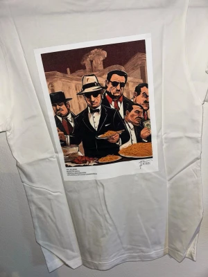 T-shirt med tryck - Säljer en stilren och snygg T-shirt med tryck från Fiore Studios   T-shirten är vit med ett snyggt vintageinspirerat tryck på ryggen. Enkel att matcha och passar perfekt till både jeans och shorts.  Bra kvalitet och håller länge.  -Kolla min profil för mer liknande tröjor med andra motiv. -Om du hittar andra tröjor i profilen som du tycker om, skriv till mig så får du ett ”paketpris”   Storlek: XS Aldrig använd. Den har bara legat i garderoben i ett år.