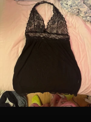 Svart spets halterneck topp - Svart halterneck topp med djup urringning och överdel i blommig spets. Toppen har en liten rosett framtill och nederdelen är i tunn mesh som faller löst. Perfekt för en trendig och feminin look. Priset går att diskutera ❣️