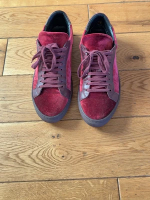 Vinröda sneakers i sammet - Säljer ett par vinröda sneakers från Antony Morato i sammet med matchande skosnören och detaljer i mörkrött läder. Skorna har en låg profil och en mörk sula. De är i bra skick, storlek 42. Inga defekter. Hör av er vid funderingar.