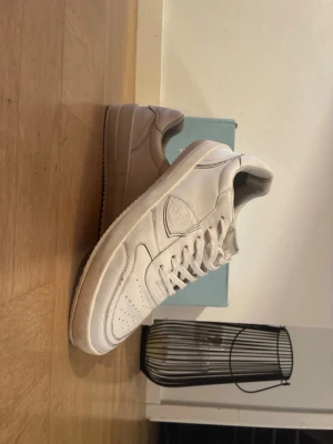 Vita philipmodell skor - Stilrena vita philipmodell sneakers i läder med klassisk siluett och perforerade detaljer på tån. Skorna har vita snören och en vit sula med diskreta sömmar. Passar perfekt till jeans eller shorts för en clean look.