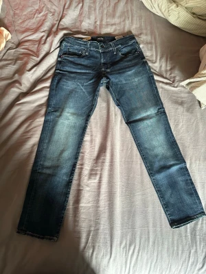 Mörkblå Jack & Jones jeans  - Säljer ett par mörkblå jeans från Jack & Jones i modellen slim/glenn som aldrig är använda i storleken 32x30. Hör av dig om du har några funderingar!