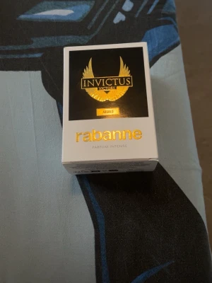 Invictus Victory Absolu Parfym - Parfymen Invictus Victory Absolu från Rabanne kommer i en snygg svart troféformad flaska med gulddetaljer och en elegant vit och svart förpackning med guldtext. Doften är intensiv och exklusiv, perfekt för dig som vill sticka ut.