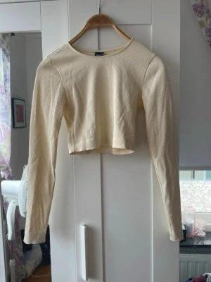Ljusgul croppad långärmad topp - Trendig ljusgul croppad topp med långa ärmar och rund halsringning. Tillverkad i ribbad bomull som ger en skön och stretchig känsla. Perfekt att matcha med  jeans, kjol för en snygg look eller ha när du tränar.                                                                          Är öppen för att förhandla priset🌸