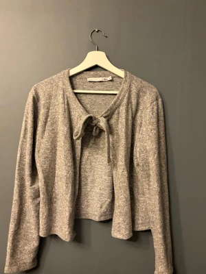 Grå cardigan med knytning från 157 -  cardigan från 157 med knytband framtill. Tröjan har lång ärm och är tillverkad i ett mjukt, stretchigt material. 