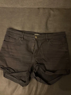 Svarta jeans shorts med dragkedja - Säljer svarta jeans shorts. Shortsen har uppvikta benslut, bälteshällor och stängs med dragkedja och knapp. 
