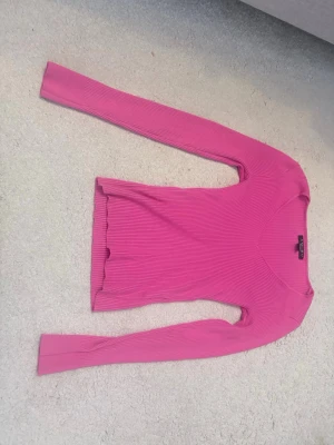 Rosa ribbstickad tröja - Snygg rosa ribbstickad tröja med lång ärm och v-ringad hals. Tröjan har en figurnära passform och är tillverkad i ett mjukt, stretchigt material som passar perfekt till jeans eller kjol.