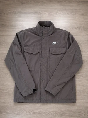 Nike Woven M65 jacka Stl S - En höst jacka från nike i mycket bra skick.  Inga tecken på användning.  Storlek S  Fungerande fickor och dragkedja.   62% bomull 38% Nylon  Längd: 72cm Armhålsbredd: 50cm  💭Skicka meddelande vid frågor! 🚛Skickar inom 24H! ✅Pris kan diskuteras! 📦Bundle rabatter upp till 15%  Sökord: Höst, jacka, vindjacka, windbreaker, september, kofta,   #nike #vindjacka #windbreaker #höst