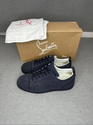 Glittriga blå Louboutin sneakers - Säljer ett par blå sneakers från Christian Louboutin med glittrig finish och klassisk låg siluett. Skorna har svarta snören, vit insida och diskreta detaljer som ger en lyxig känsla. Perfekta för dig som vill sticka ut med stil.