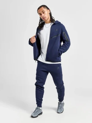 Mörkblå Nike tech - Snygg mörkblå Nike tech hoodie och byxor med  dragkedja och huva. Hoodien har en modern design med svarta detaljer, ficka på ärmen och raka linjer över bröstet. Tillverkad i ett mjukt material som känns bekvämt och passar perfekt till en avslappnad stil.