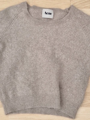 Beige stickad tröja från Acne Studios - Storleken är L men jag kan ha den som en off shoulder tröja och jag brukar ha storlek XXS/XS. Mysig beige stickad tröja från Acne med rund halsringning och ribbade muddar. Tröjan har en avslappnad passform och är tillverkad i ett mjukt, luddigt material som känns lyxigt och trendigt. Perfekt för lager på lager och enkel att styla.