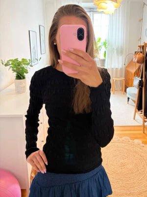 Svart långärmad smockad topp - Säljer en svart långärmad topp med jättefin struktur, smockad struktur i tyget. Tyget är stretchigt. Använd, men fortfarande i ett bra skick. Kontakta vid frågor💗