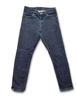 ( Tiger of sweden)Mörkblå slim jeans med klassisk look - Snygga mörkblå jeans i slim passform med fem fickor och klassisk knappgylf från tiger of sweden. Jeansen har en enkel design utan synliga loggor och är tillverkade i mjuk bomull med lite stretch för extra komfort.
