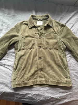 Olivgrön overshirt i manchester - Riiiktigt snygg olivgrön overshirt i manchestertyg med krage och knäppning framtill. Två stora bröstfickor och raka ärmar. Inga defekter 