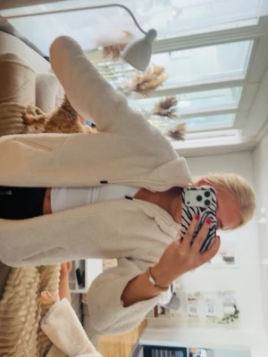 Beige teddyjacka med dragkedja - Mysig beige teddyjacka med dragkedja framtill och hög krage. Jackan har en avslappnad passform och är gjord i fluffigt teddy-material som känns riktigt skönt. Perfekt för att hålla värmen under kyliga dagar och ger en trendig look.