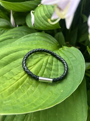 Svart flätat läderarmband - Snyggt svart armband i flätat läder med ett stilrent magnetlås i silverfärgad metall. Perfekt accessoar för dig som gillar en enkel men cool look. Passar till det mesta och är lätt att matcha med andra smycken. Har flera Stycken så ifall ni är intresserade kontakta mig☺️