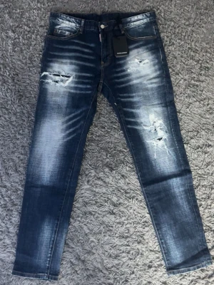 Dsquared2 jeans - Blåa Dsquared2 jeans med slitningar. Knappt använda. Precis som nya. Storlek 34, passar alla mellan 178-188. Top kvalitet!