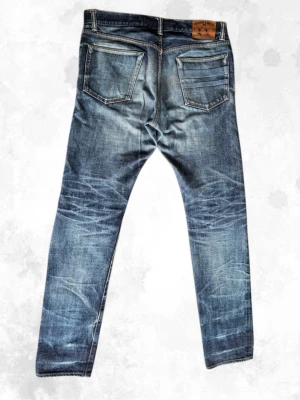 Limited Edition Momotaro  - Ett par Momotaro selvedge-jeans Limited Edition som motsvarar ungefär storlek 34/34. Se måtten nedan.  Jeansen är i mycket bra skick, men har några mindre fläckar som man kan se på bild 4 och 5.  Skicka gärna ett meddelande om du har några frågor!  Mått  * Midja: 45 cm * Grenhöjd (rise): 27 cm * Lårvidd: 30 cm * Innerbenslängd (inseam): 86 cm * Total längd: 108 cm * Benöppning: 16,5 cm
