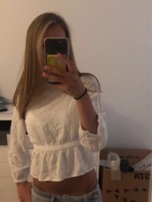 Vit volangblus med resår i midjan - Säljer en söt vit blus med vita prickar och volang nedtill och resår i midjan. Blusen har långärmade ärmar.💓