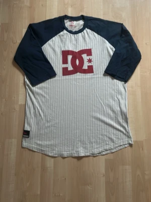 Randig DC t-shirt med trekvartsärm - Vintage DC T-shirt. Köpt secondhand därav helt okej skick med tanke på att märket på bröstet spruckit lite. Stl XL i herrstolekar så passar perfekt för en mer oversized look. Kom privat vid fler frågor eller likande! Checka gärna in resten av min profil!!