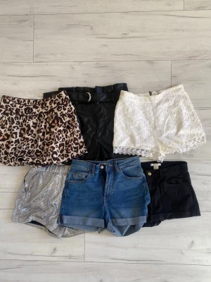 Mix av shorts i olika stilar, paketpris - Fem par shorts i olika material och färger: leopardmönstrade, svarta i skinnimitation med bälte, vita spets, silverglittriga, svarta samt klassiska blå jeansshorts. Perfekt för dig som vill variera din stil och gillar att mixa olika looks. Tre stycken linnen på köpet