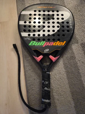 Bullpadel Vertex paddelrack.  - Bullpadel Vertex 02 Woman/Junior. Modellen är en högkvalitativt padelracketen och är en  juniorkopia av vuxenracketet som användes av proffsspelarna Cata Tenorio och Delfi Brea, vars signaturer också pryder racketets yta.