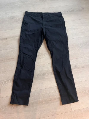 Svarta slim fit chinos från H&M - Snygga svarta chinos från H&M i slim fit-modell. Byxorna har en klassisk design med raka ben och normal midja. Tillverkade i ett mjukt och bekvämt material som passar perfekt till en avslappnad stil. Enkla att matcha med olika plagg.