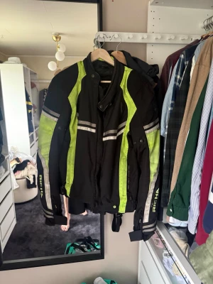 Svart och neongul MC-jacka från Richa - Säljer en svart motorcykeljacka från Richa med neongula detaljer och reflexränder. Jackan har hög krage, dragkedja framtill och justerbara ärmslut. Perfekt för dig som vill synas på vägen och ha en sportig look.