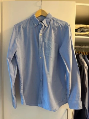 Ljusblå skjorta från Gap medium - Klassisk ljusblå skjorta från Gap i slim fit-modell. Skjortan har button-down krage, bröstficka och vita knappar framtill. Tillverkad i mjuk bomull och passar perfekt till både jeans och chinos. Medium