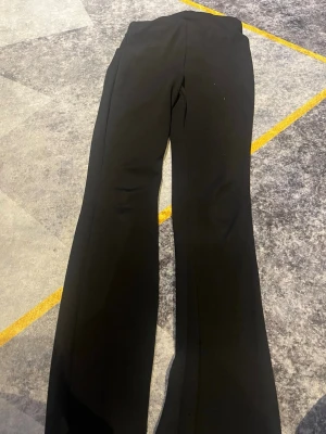 Svarta kostymbyxor från H&M XS - Säljer ett par svarta kostymbyxor från H&M i storlek XS. Byxorna har en klassisk rak passform med lätt utsvängda ben och hög midja. Perfekta för en clean och stilren look. Materialet är mjukt och följsamt för extra komfort.