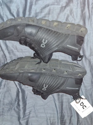Svarta On Running sneakers - Snygga svarta sneakers från On Running med sportig design och robust sula. Skorna har ventilerande meshpartier, diskreta loggor på sidan och slitstarka material. Perfekta för dig som gillar en clean och modern look.
