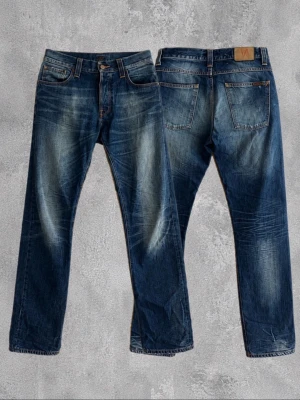 Blå raka jeans med slitningar - Ett par jävligt feta Nudie Jeans i den populära passformen Average Joe. Storlek 32/36. Riktigt sköna fades på dem. Som nya.