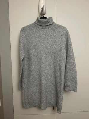 Grå poloklänning stickad - Mysig grå stickad poloklänning med lång ärm och ribbade muddar vid ärmslut och nederkant. Jättefint skick, och en mysig klänning för årets kallare dagar. 