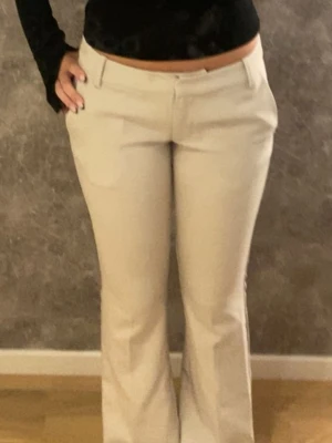 Beiga lågmidjade bootcut kostymbyxor  - Snygga ljus beiga kostymbyxor med bootcut-passform, dom är helt oanvända, har inte kommit till användning, skitsnyggt att styla med en svart tröja!! Köpte för 500, pris kan diskuteras vid köp!💕