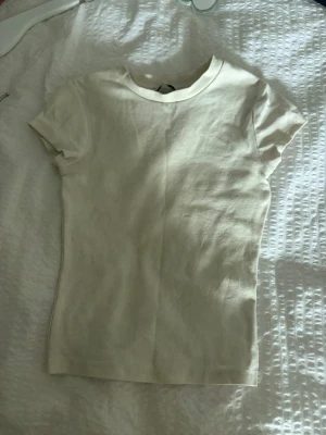 Vit basic t-shirt - En enkel vit t-shirt från Bershka med rund hals och korta ärmar. Tillverkad i mjuk bomull som känns skön mot huden. Perfekt att matcha med jeans eller shorts för en clean och stilren look.