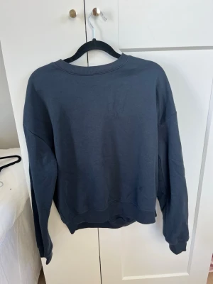 Mörkblå oversized sweatshirt - En enkel och stilren mörkblå sweatshirt med rund halsringning och avslappnad passform. Tröjan har långa ärmar och ribbade muddar vid ärmslut och nederkant. Perfekt för en chill och casual look.