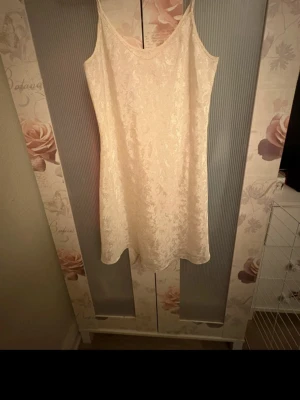 Beige nattlinne med spetsmönster - Säljer ett elegant beige nattlinne med tunna axelband och vackert spetsinspirerat mönster i tyget. Nattlinnet har en fin form vid midjan och  är 40 år gammalt då både jag och min mor haft den 