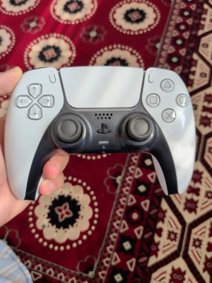 Vit  PS5 DualSense handkontroll - Säljer en stilren vit och svart PlayStation 5 DualSense handkontroll. Den har ergonomisk form, två analoga spakar, touchpad och klassiska PlayStation-knappar. Tillverkad i tålig plast och passar perfekt för gaming på PS5. Jag har även installerat TMR spakar i den. KontrollKungen på tiktok. 