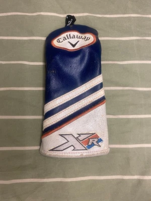 Callaway XR blå headcover - Snygg blå headcover från Callaway med XR-logga. Tillverkad i konstläder med vita och röda detaljer samt broderad Callaway-text. Perfekt för att skydda din golfklubba och ge bagen en sportig look.