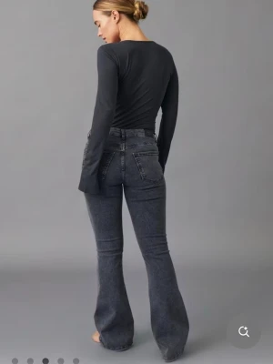 Mörkgrå bootcut jeans med hög midja - Säljer ett par mörkgrå bootcut jeans med hög midja och klassiska fem fickor. Jeansen har en lätt tvättad look och utsvängda ben som ger en snygg siluett. Perfekta att styla med en enkel topp eller hoodie.