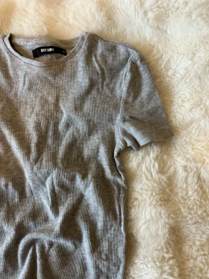 Grå t-shirt  - Säljer en enkel och stilren grå ribbad t-shirt från BikBok i storlek XS. Nästan helt ny!!
