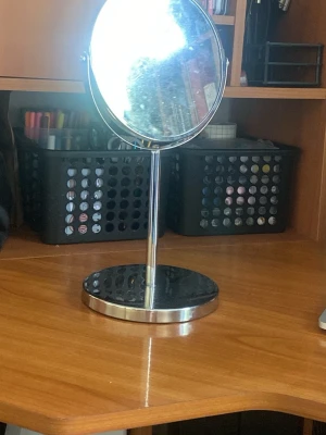 Rund sminkspegel med förstoringsfunktion - Snygg rund sminkspegel i silverfärgad metall med stabil fot och ställbar ram. Ena sidan har 3x förstoring, perfekt för detaljerad makeup. Stilren och enkel design som passar på alla sminkbord.