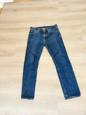 Levi's 513 blå jeans herr - Säljer ett par klassiska blå Levi's 513 jeans med rak passform och fem fickor. Jeansen har snygga kontrastsömmar och är tillverkade i slitstarkt denim. Perfekta för en avslappnad och tidlös stil.