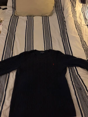 Mörkblå stickad tröja från Ralph Lauren - Tjena, säljer denna feta stickade Ralph lauren sweatshirten. Den är i bra skick förutom att det är ett pyttelitet hål i axeln men som inte syns vid användning samt att den även är lite utdragen runt halsen.Original pris~ 2595kr, priset är inte hugget i sten. Skriv om ni undrar något! 
