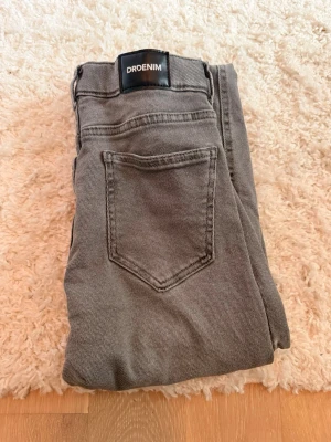 Gråa bootcut jeans från DRDENIM - Säljer ett par gråa bootcut jeans från DRDENIM. Jeansen har klassisk femficksdesign, normal midja och raka ben som går ut lite nedtill. Materialet är mjukt denim och färgen är en snygg tvättad grå. Perfekta till en avslappnad stil.