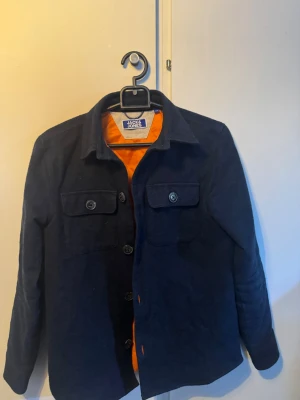  Overshirt - Mörkblå overshirt ifrån Jack & Jones. Passar de 152 och lite ner/uppåt skulle jag säga. Knappast använd då den blev för liten strax efter jag köpte. Inga skavanker eller märken på den. Kom med bud om priset inte duger
