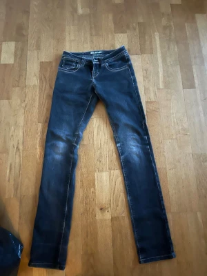Mörkblå skinny jeans från Blend - Snygga mörkblå typ skinny jeans från Blend med klassiska fem fickor och vita kontrastsömmar. Jeansen har slitningar på låren och bakfickor med dekorativa sömmar. Perfekta för en trendig och avslappnad stil.
