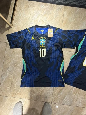 Brasilien Neymar JR matchtröja blå - Snygg blå Brasilien matchtröja med Neymar JR och nummer 10 på ryggen. Tröjan har gula och gröna detaljer, korta ärmar och rund hals. Perfekt för dig som älskar fotboll och vill stötta landslaget. Tillverkad i lätt och ventilerande material.