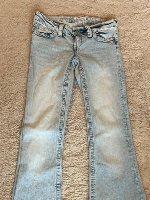 Ljusblå bootcut jeans med brodyr - Bootcut jeans med rosa brodyr på bakfickorna