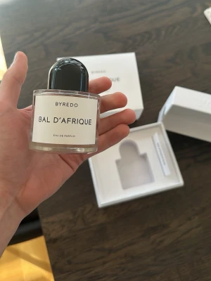 Byredo Bal d'Afrique Eau de Parfum - Byredo Bal d'Afrique Eau de Parfum i elegant vit kartong med stilren svart text. Förpackningen har en lyxig känsla och parfymen är känd för sin unika doftprofil inspirerad av afrikanska influenser. Perfekt för dig som gillar exklusiva dofter.*parfymen kommer helt ny och inplastad, detta är min personliga parfym på bilderna* 